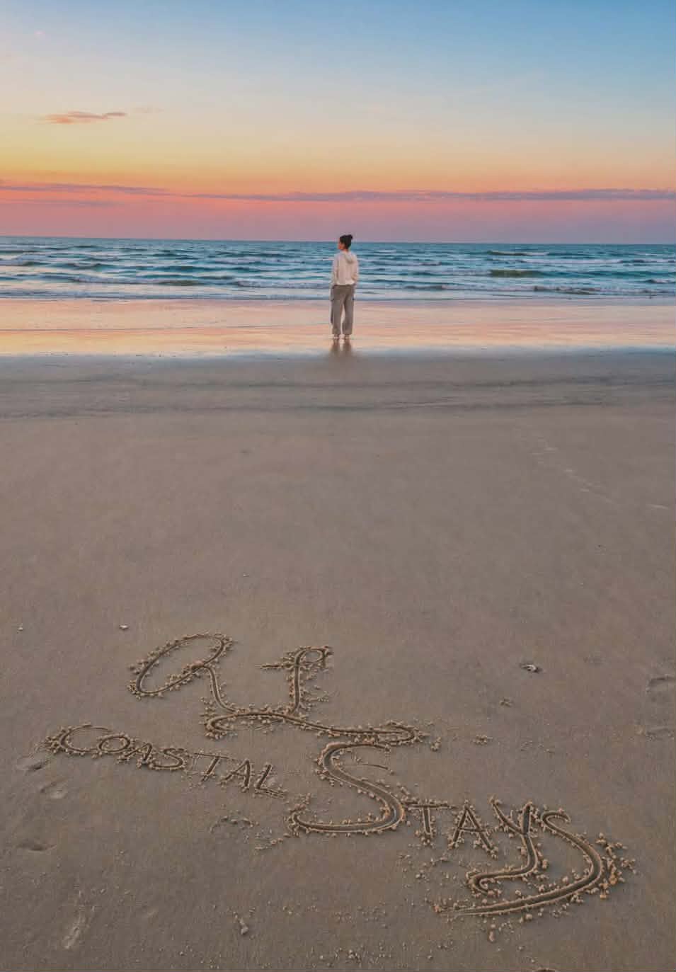 R&L Coastal Stays written in the sand at sunset